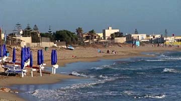 spiaggia-mediterraneo-delfino-edifici-ombrelloni